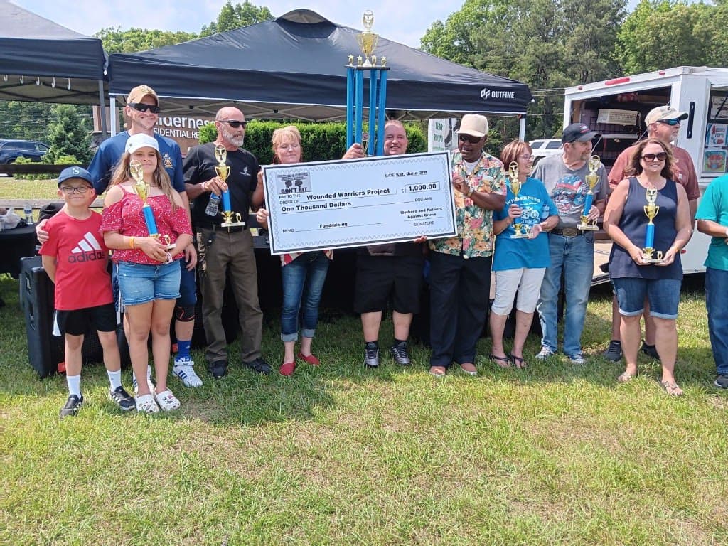 Group presenting a ceremonial $1,000 check to the Wounded Warrior Project from Mothers and Fathers Against Crime at an outdoor fundraising event